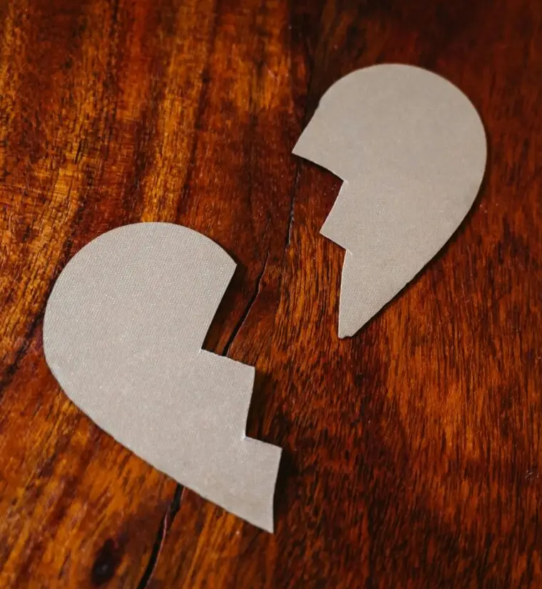A rustic wooden puzzle heart, partially broken, symbolizing the raw and unfinished nature of grief.